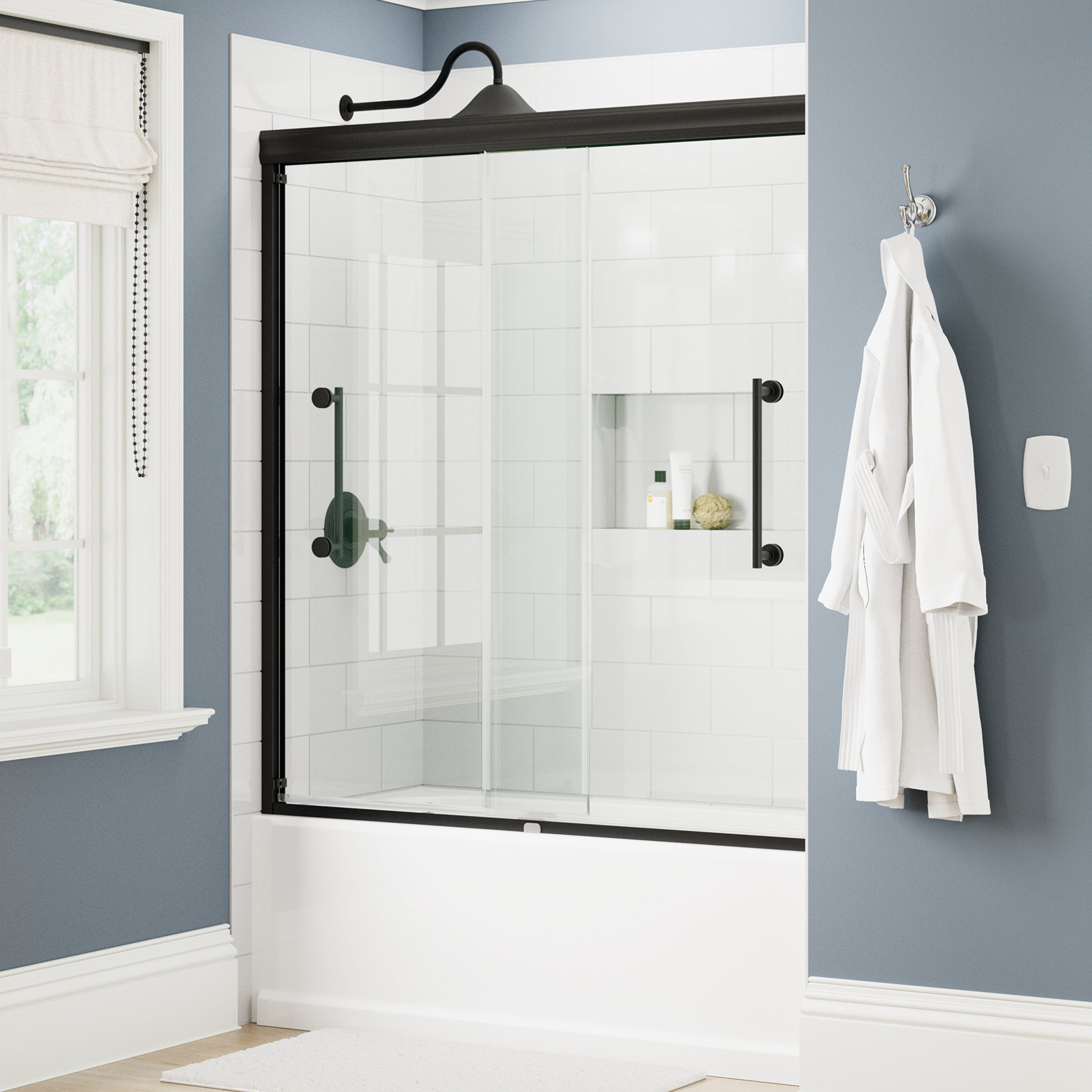 Bathroom with a glass shower enclosure, white bathrobe, and toiletries.