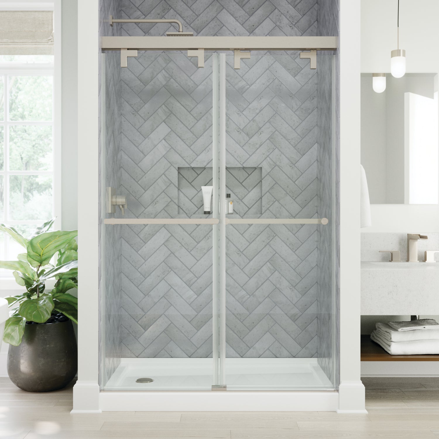 Modern shower enclosure with glass doors and chevron-patterned wall tiles in a bathroom setting.